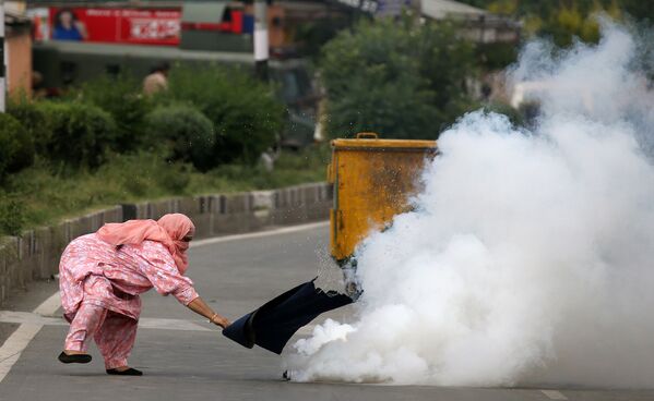 امرأة تحاول إبعاد قنبلة غاز مسيل للدموع خلال المواجهات مع الشرطة في كشمير، 17 أغسطس/ آب 2016 - سبوتنيك عربي