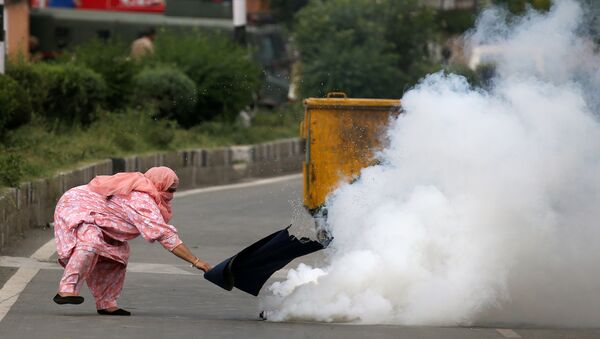 امرأة تحاول ابعاد قنبلة غاز مسيل للدموع خلال التصادمات مع الشرطة في كشمير، 17 أغسطس/ آب 2016 - سبوتنيك عربي
