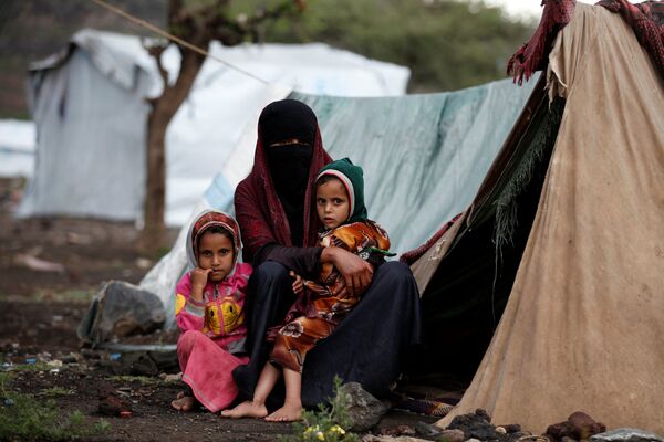 امرأة مع طفلتيها تجلس قبالة خيمتها بمخيم للنازحين في أحد شوارع مدينة صنعاء، اليمن 15 أغسطس/ آب 2016 - سبوتنيك عربي