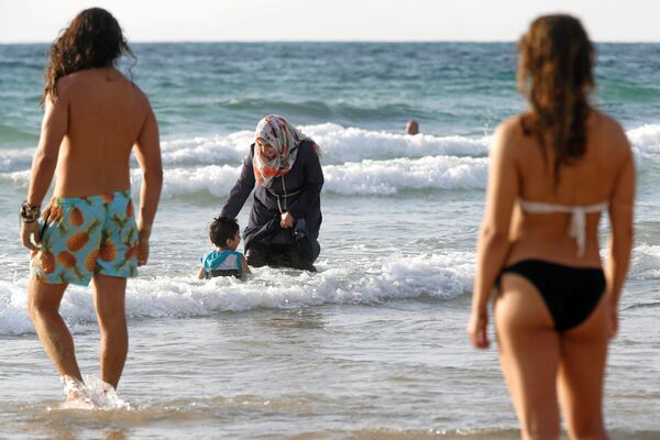 امرأة محجبة وطفلها في البحر على شاطئ تل-أبيب، 22 أغسطس/ آب 2016 - سبوتنيك عربي