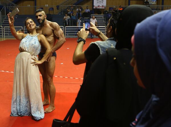 فتاة تأخذ صورة سيلفي مع أحد المشاركين في مسابقة كمال الأجسام ببيروت - سبوتنيك عربي