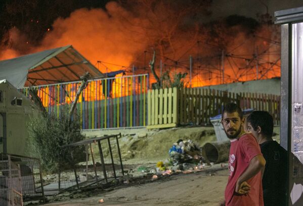 المهاجرون يشاهدون النار في مخيم للاجئين في شمال الجزيرة اليونانية ليسبوس - سبوتنيك عربي