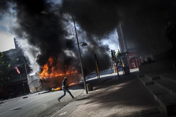 أحد المتظاهرين يجري في الشارع بعد انفجار باص في جوهانسبرغ، جنوب أفريقيا 10 أكتوبر/ تشرين الأول 2016 - سبوتنيك عربي