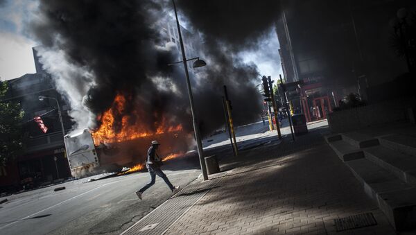 أحد المتظاهرين يجري في الشارع بعد انفجار باص في جوهانسبرغ، جنوب أفريقيا 10 أكتوبر/ تشرين الأول 2016 - سبوتنيك عربي