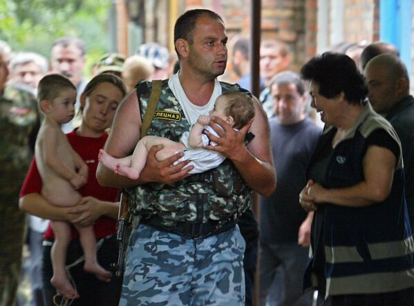 جندي من وحدة القوات الخاصة الروسي يحمل طفلاً، كان رهينة بمدرسة في بيسلان، أوسيتيا الشمالية - سبوتنيك عربي