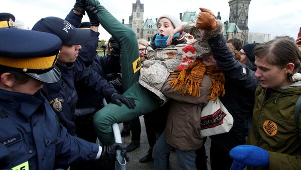 شاب يحاول الافلات من من أفراد الشرطة خلال مظاهرات اجتاحت أونتاريو، كندا 24 أكتوبر/ تشرين الأول 2016 - سبوتنيك عربي