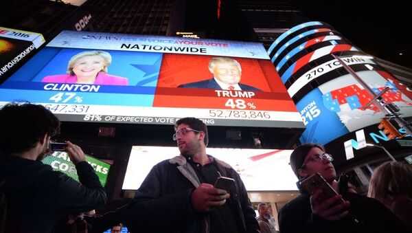أشخاص يقفون على خلفية شاشة تظهر النتائج الأولية للتصويت في الانتخابات الرئاسية الأمريكية في ساحة تايمس سكوير، نيويورك 8 نوفمبر/ تشرين الثاني 2016 - سبوتنيك عربي