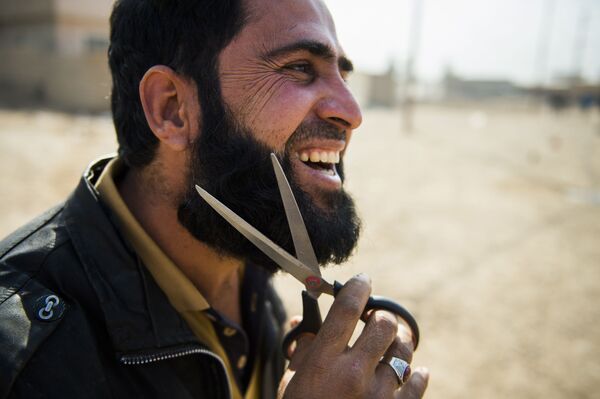 رجل عراقي يقوم بقص شعر ذقنه بواسطة مقص، وذلك لدى وصوله المناطق التي حررتها القوات العراقية بحي الانتصار بالموصل، 7 نوفمبر/ تشرين الثاني 2016 - سبوتنيك عربي