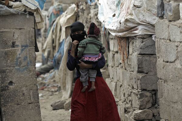 امرأة تحمل طفلها، من مجتمع الخدام، تسير وسط أحد الأحياء الفقيرة في العاصمة صنعاء، اليمن 9 نوفمبر/ تشرين الثاني 2016 - سبوتنيك عربي