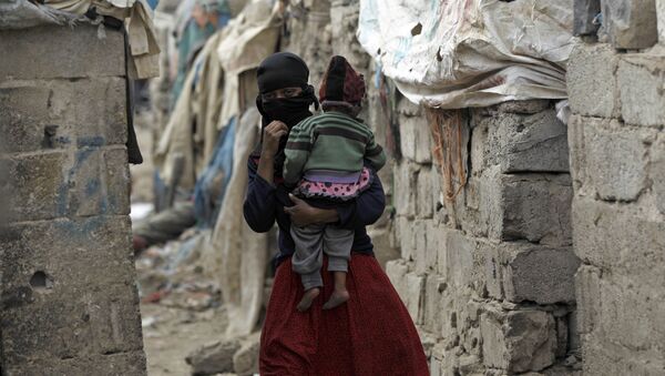 امرأة تحمل طفلها، من مجتمع الخدام، تسير وسط أحد الأحياء الفقيرة في العاصمة صنعاء، اليمن 9 نوفمبر/ تشرين الثاني 2016 - سبوتنيك عربي