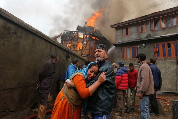 رجل يهدئ قريبته التي تبكي إثر حريق اشتعل في منزلها في سريناجار، الهند 21 نوفمبر/ تشرين الثاني 2016 - سبوتنيك عربي