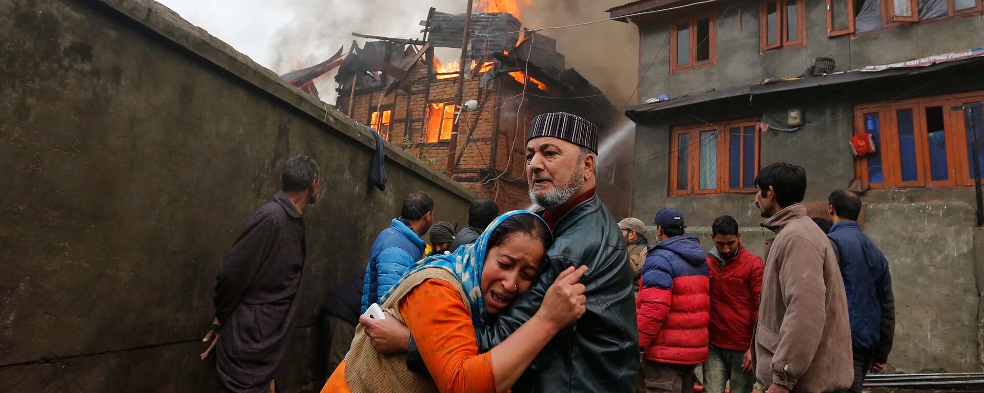 رجل يهدئ قريبته التي تبكي إثر حريق اشتعل في منزلها في سريناجار، الهند 21 نوفمبر/ تشرين الثاني 2016 - سبوتنيك عربي, 1920, 16.12.2021