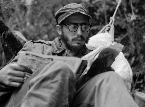 الزعيم الكوبي فيدل كاسترو وهو جالس يقرأ في قاعدته العسكرية في جبال سيرا مايسترا، كوبا 1957 - سبوتنيك عربي