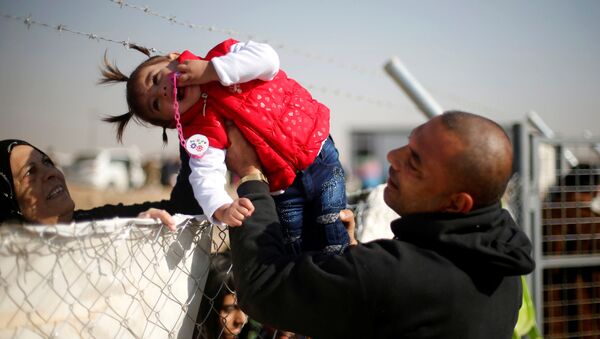 نازح عراقي من الموصل، يمرر ابنته لترى جدتها من خلال عازل بمخيم للنازحين، العراق 28 نوفمبر/ تشرين الثاني 2016 - سبوتنيك عربي