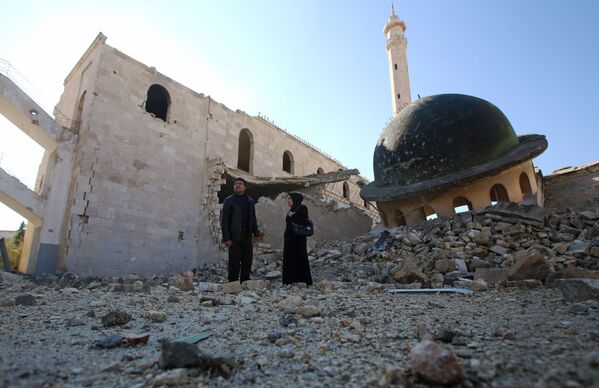 كيفا جاويش وزوجها تاج الدين أحمد يسيران وسط ركام المنازل والمسجد بحي هنانو في حلب، وهذه زيارتهما الأولى للمكان منذ أربعة أعوام، 4 ديسمبر/ كانون الأول 2016 - سبوتنيك عربي