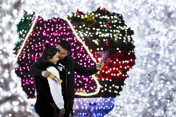 حبيبان، رجل وامرأة يلتقطان صورة سيلفي على خلفية أضواء أعياد رأس السنة في بكين، 1 ديسمبر/ كانون الأول 2016 - سبوتنيك عربي