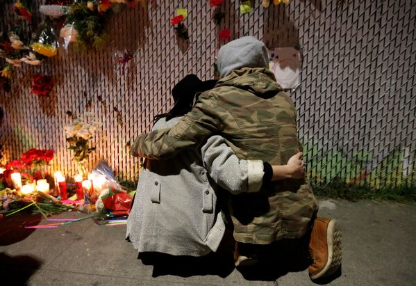زوجان يقفان أمام أكاليل الزهور والشموع لإحياء ذكرى ضحايا الحريق الذي نشب في مخزن تجاري في أوكلاند، كاليفورنيا  4 ديسمبر/ كانون الأول 2016 - سبوتنيك عربي