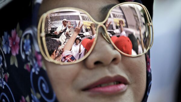 حشد من المتظاهرين أمام محكمة بشمال جاكرتا تنعكس في نظارة شمسية لامرأة، اندونيسيا 13 ديسمبر/ كانون الأول 2016 - سبوتنيك عربي