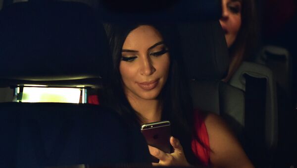 US reality TV star Kim Kardashian looks at her iPhone as she sits in a car after visiting the genocide memorial, which commemorates the 1915 mass killing of Armenians in the Ottoman Empire, in Yerevan on April 10, 2015 - سبوتنيك عربي