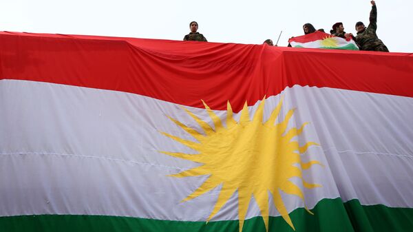 Iraqi Kurdish youths wave a national flag as they stand above a giant flag of Kurdistan during celebrations of Flag Day on December 17, 2015 - سبوتنيك عربي
