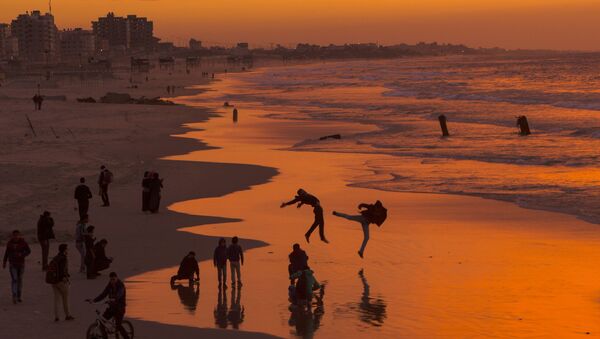 مواطنون فلسطينيون على شاطئ البحر في مدينة غزة خلال غروب الشمس، قطاع غزة، فلسطين 10 يناير/ كانون الثاني 2017 - سبوتنيك عربي