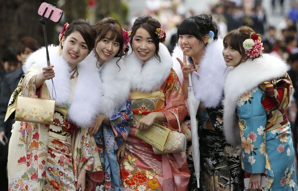 الفتيات اليابنيات يرتدين الزي التقليدي كيمونو في إحدى الحدائق الترفيهية بطوكيو، ويأخذن صورة سيلفي خلال يوم سن البلوغ في اليابان، 9 يناير/ كانون الثاني 2017 - سبوتنيك عربي