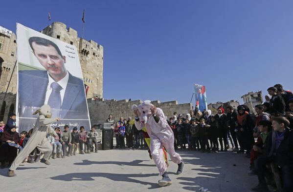 مواطنون عند قلعة حلب وصورة الرئيس السوري بشار الأسد - سبوتنيك عربي