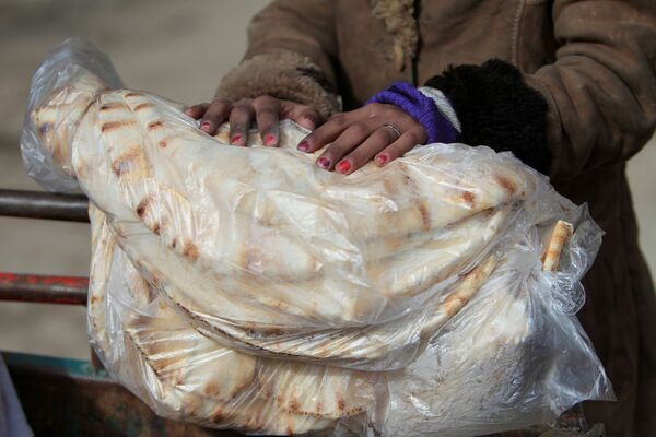 امرأة تحمل خبزاً في حلب، سوريا 30 يناير/ كانون الثاني 2017 - سبوتنيك عربي
