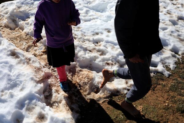 مروان (13 عاماً) يسير على طبقة الثلج التي غطت الأرض بجوار منزله في قرية أفلو بجبال الأطلس الصحراوي، الجزائر 26  يناير/ كانون الثاني 2017 - سبوتنيك عربي