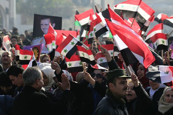 سوريون يحملون صور الرئيس بشار الأسد وأعلام سوريا في حلب - سبوتنيك عربي