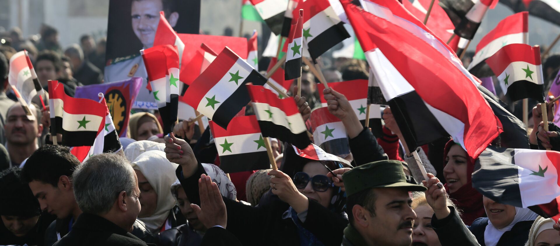 سوريون يحملون صور الرئيس بشار الأسد وأعلام سوريا في حلب - سبوتنيك عربي, 1920, 09.04.2021