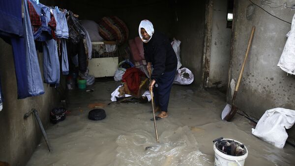 امرأة فلسطينية تقوم بتنظيف البيت من آثار فياضانات نتيجة أمطار غزيرة انهالت على مخيم جباليا، قطاع غزة، فلسطين 16 فبراير/ شباط 2017 - سبوتنيك عربي