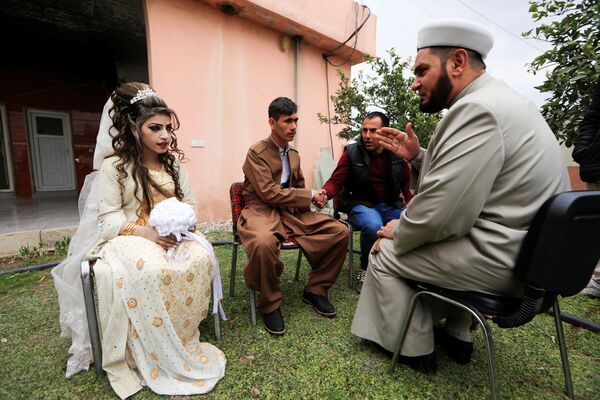 المتزوجان حديثاً، حسين زينو زعنون (26 عاما) وشهد (16 عاما) خلال مراسم الزواج، يستمعان إلى المفتي، في مخيم خازر للنازحين من الموصل، العراق 16 فبراير/ شباط 2017 - سبوتنيك عربي