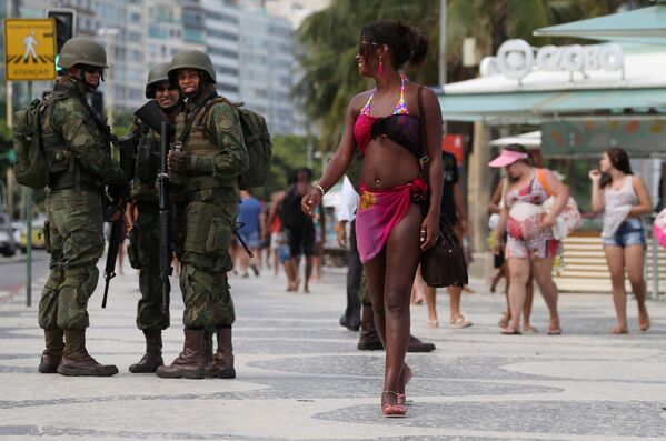 دورية الشرطة البرازيلية تنظر إلى امرأة تعبر الطريق إلى شاطئ كوباكابانا، البرازيل 14 فبراير/ شباط 2017 - سبوتنيك عربي
