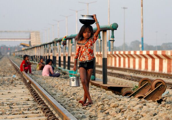 طفلة تحمل وعاء بعد تعبئته بالماء وتسير على السكة الحديدية، الهند 28 فبراير/ شباط 2017 - سبوتنيك عربي