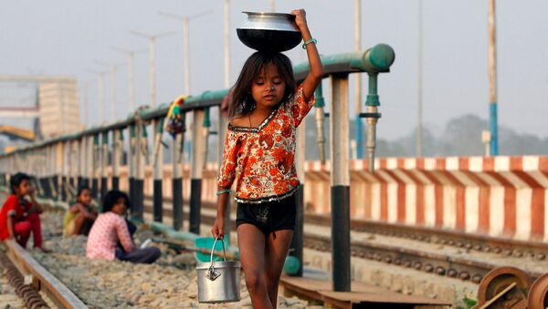 طفلة تحمل وعاء بعد تعبئته بالماء وتسير على السكة الحديدية، الهند 28 فبراير/ شباط 2017 - سبوتنيك عربي