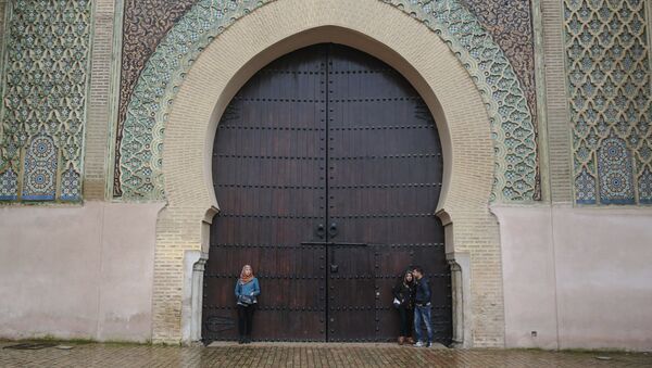 أشخاص يحتمون من المطر بمدخل مدينة مكناس التاريخية الذي بني في القرن الـ 18 بالقرب من مكناس، المغرب 23 فبراير/ شباط 2017 - سبوتنيك عربي