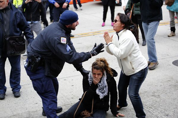 أحد أفراد الشرطة الأمريكية يساعد إحدى المتظاهرات، خلال مواجهات دارت بين المتظاهرين ضد لجنة الشؤون العامة الإسرائيلية الأمريكية والمؤيدين لها في مدينة واشنطن، الولايات المتحدة 26 مارس/ آذار 2017 - سبوتنيك عربي