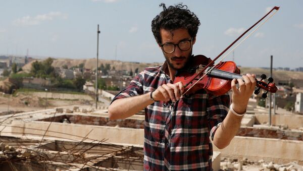 أمين مقداد يعزف على الكمان وسط ركام المباني في شرق مدينة الموصل، وذلك بعد أن كانت واقعة تحت سيطرة تنظيم داعش الإرهابي لمدة تزيد عن عامين ونصف، العراق 19 أبريل/ نيسان 2017 - سبوتنيك عربي