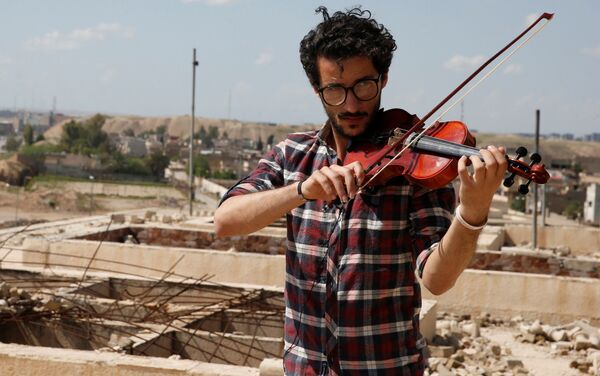 أمين مقداد يعزف على الكمان وسط ركام المباني في شرق مدينة الموصل، وذلك بعد أن كانت واقعة تحت سيطرة تنظيم داعش الإرهابي لمدة تزيد عن عامين ونصف، العراق 19 أبريل/ نيسان 2017 - سبوتنيك عربي