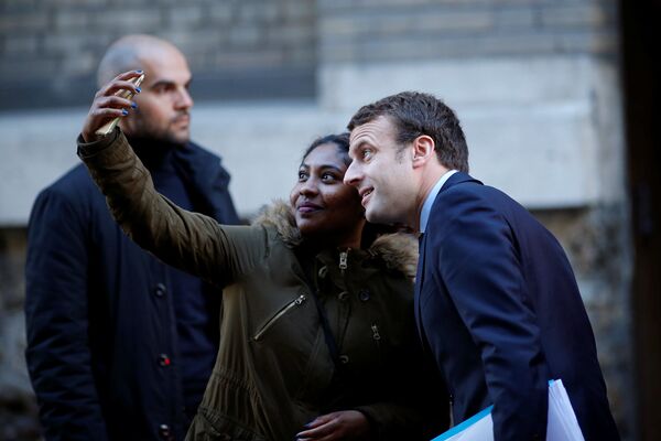 فتاة تلتقط صورة سيلفي مع المرشح للانتخابات الرئاسية الفرنسية إيمانويل ماكرون في باريس، فرنسا 2 مايو/ أيار 2017 - سبوتنيك عربي