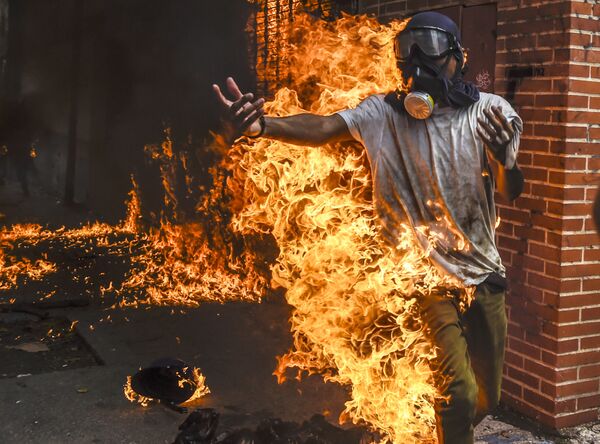 اشتعال النيران في ملابس أحد المحتجين ضد الرئيس الفنزويلي في كاراكاس، فنزويلا  3 مايو/ أيار 2017 - سبوتنيك عربي