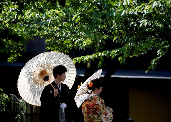 زوجان يرتديان الزي اليباني التقليدي كيمونو يلتقطان صورة لهما في كيوتو، اليابان 11 مايو/ أيار 2017 - سبوتنيك عربي
