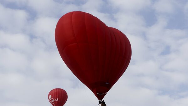 A heart-shaped hot air balloon (R) flies in the sky during the Love Cup 2016 event, ahead of Valentine's Day, in Jekabpils, Latvia, February 13, 2016 - سبوتنيك عربي