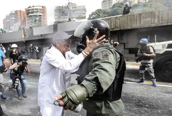 أحد المعارضين يجادل شرطي من الحرس الأمن القومي خلال الاحتجاجت في العاصمة كاراكاس، فنزويلا 22 مايو/ أيار 2017 - سبوتنيك عربي