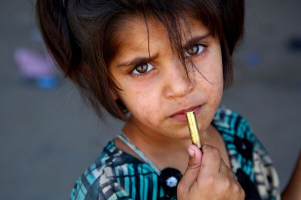 طفلة تمسك بيدها طلقة رشاش، بالقرب من مدينة الرقة السورية - سبوتنيك عربي