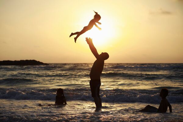 رجل يلعب مع طفلته على شاطئ البحر - سبوتنيك عربي