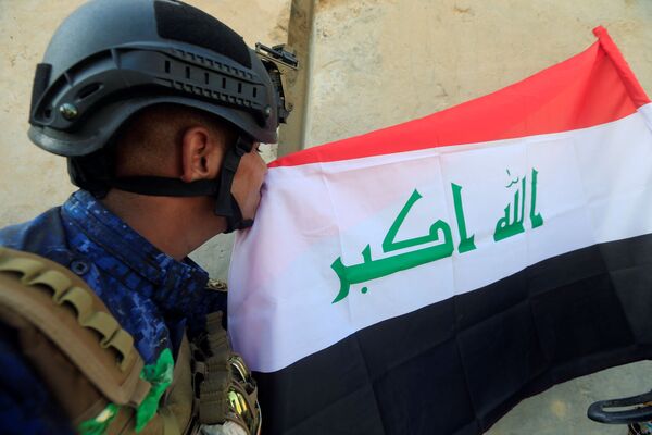أحد عناصر الشرطة العراقية يقبل العلم العراقي بعد تحرير الموصل العراقية 9  يوليو/ تموز 2017 - سبوتنيك عربي