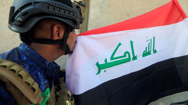 أحد عناصر الشرطة العراقية يقبل العلم العراقي بعد تحرير الموصل، العراق 9 يوليو/ تموز 2017 - سبوتنيك عربي
