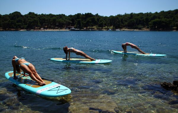 ممارسة اليوغا على ألواح الركمجة في فيروديلا على ساحل البحر الأدرياتيكي، كرواتيا، 10 يوليو/ تموز 2017 - سبوتنيك عربي
